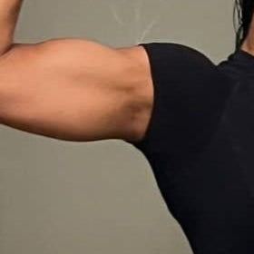 Person taking a mirror selfie showing off their arm muscles, wearing a black crop top.