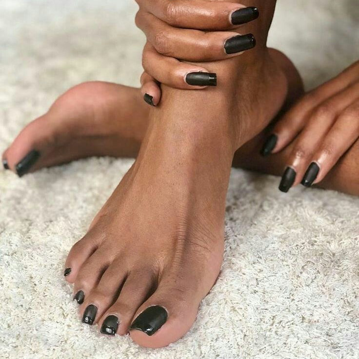 Close-up of feet with black nail polish on a light background