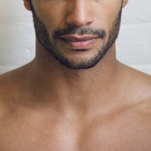 Man with a short haircut and beard against a plain background