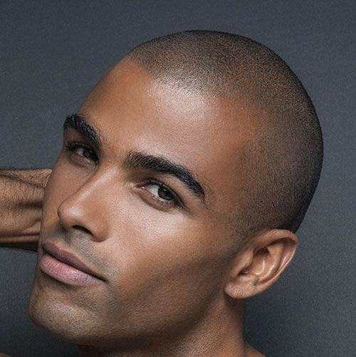 Man with a shaved head against a dark background