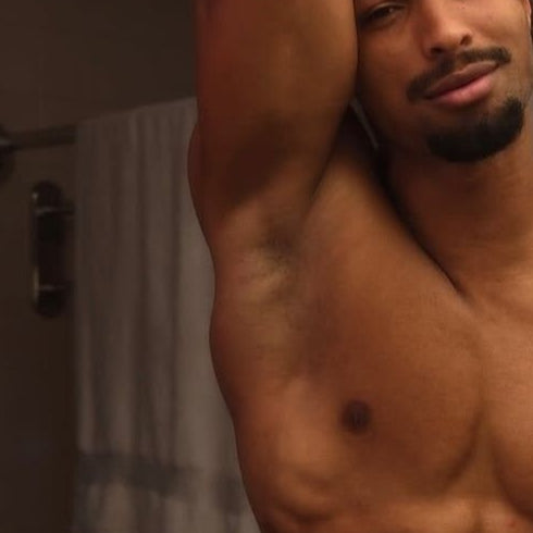 Man with a towel around his waist standing in a bathroom.