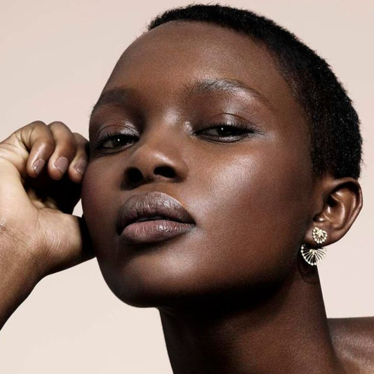 Woman with a short haircut and minimal makeup against a beige background